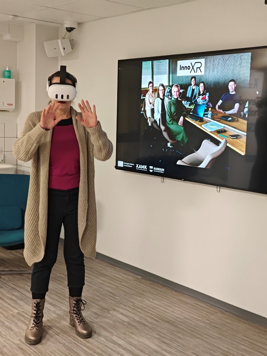 Henkilö seisoo television edessä, VR-lasit päässään.