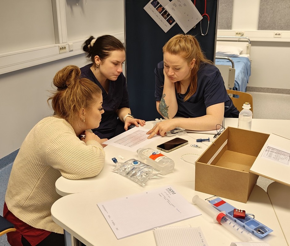Kolme naisopiskelijaa työskentelemässä pöydän äärellä.