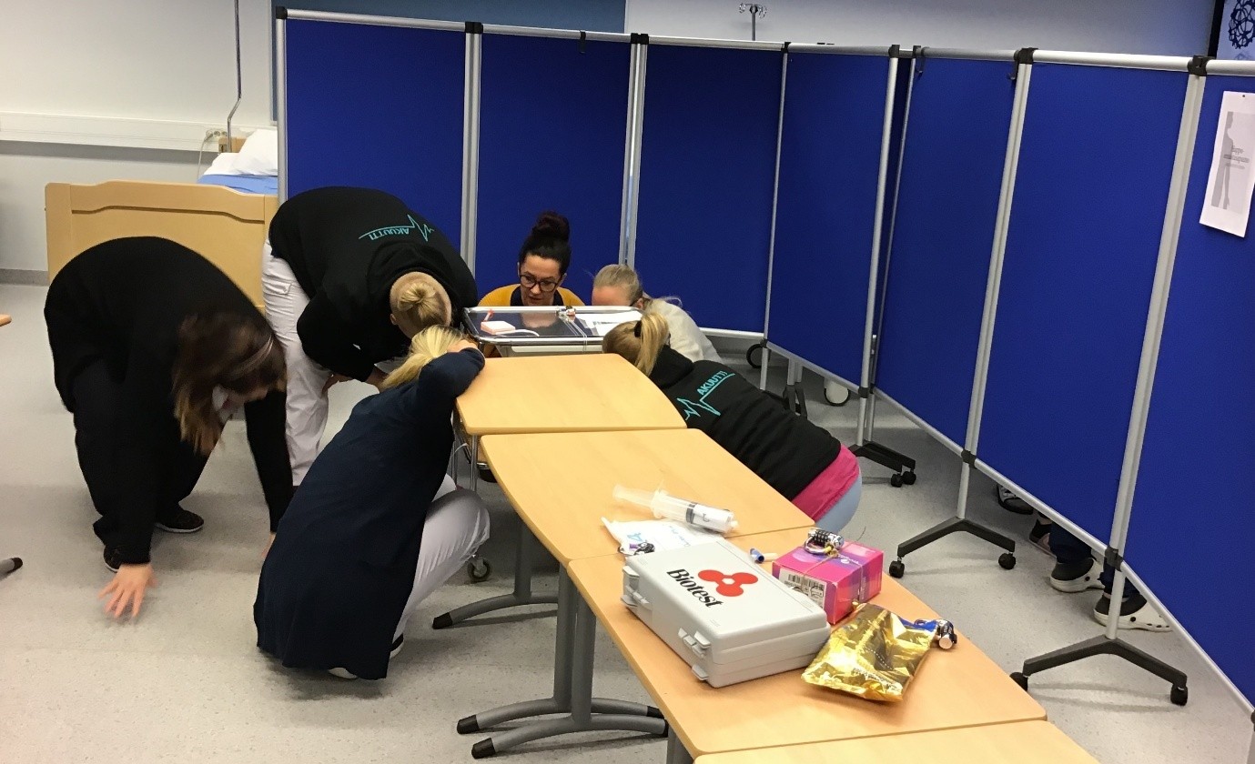 Ryhmä opiskelijoita katsomassa pöydän alle