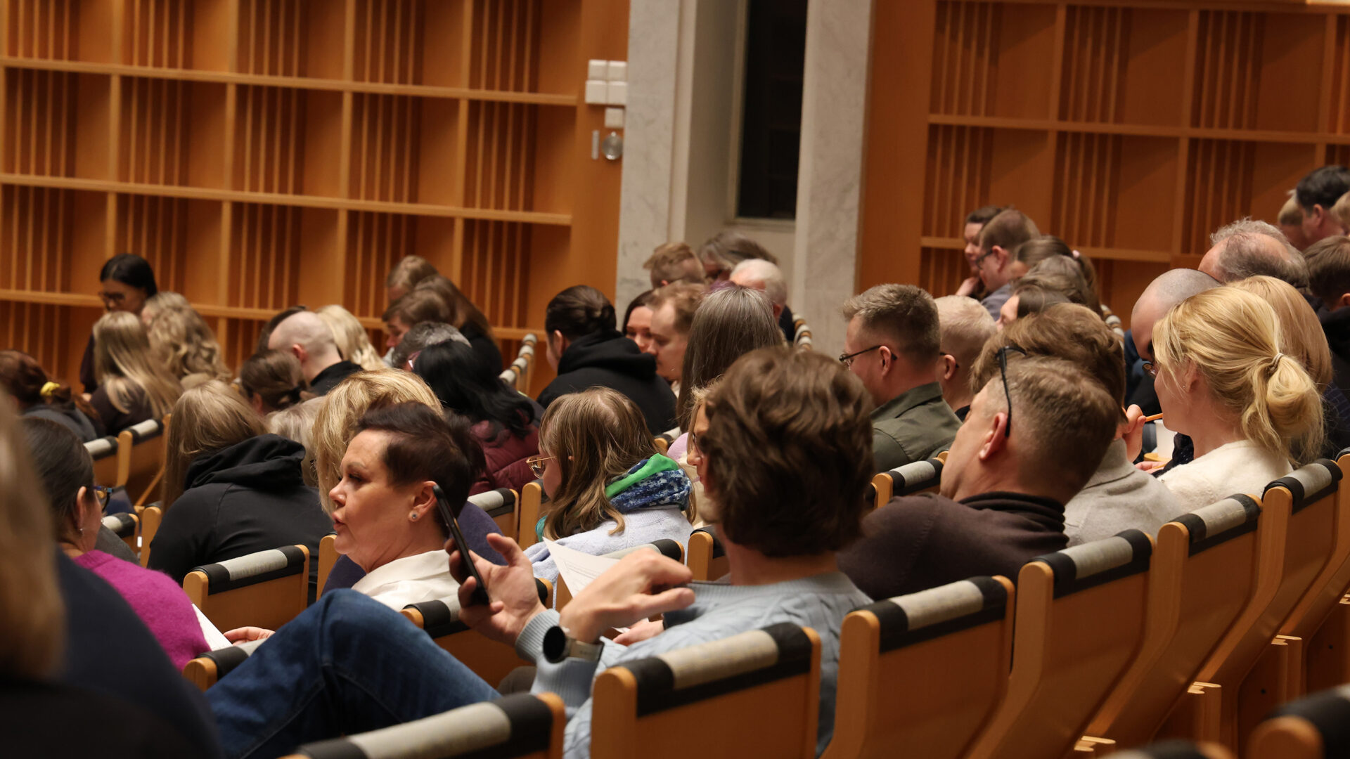 Ihmisiä istumassa luentosalissa