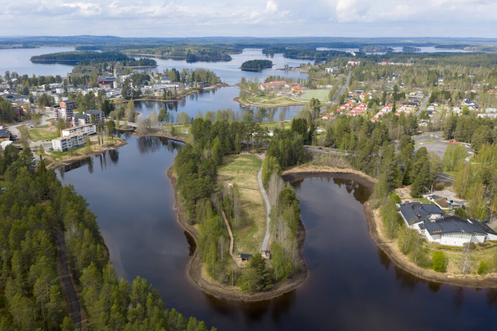 Järvimaisemassa sijaitseva kaupunki. Kuvan keskiosassa puistoalue, reunoilla kaupunkiasutusta